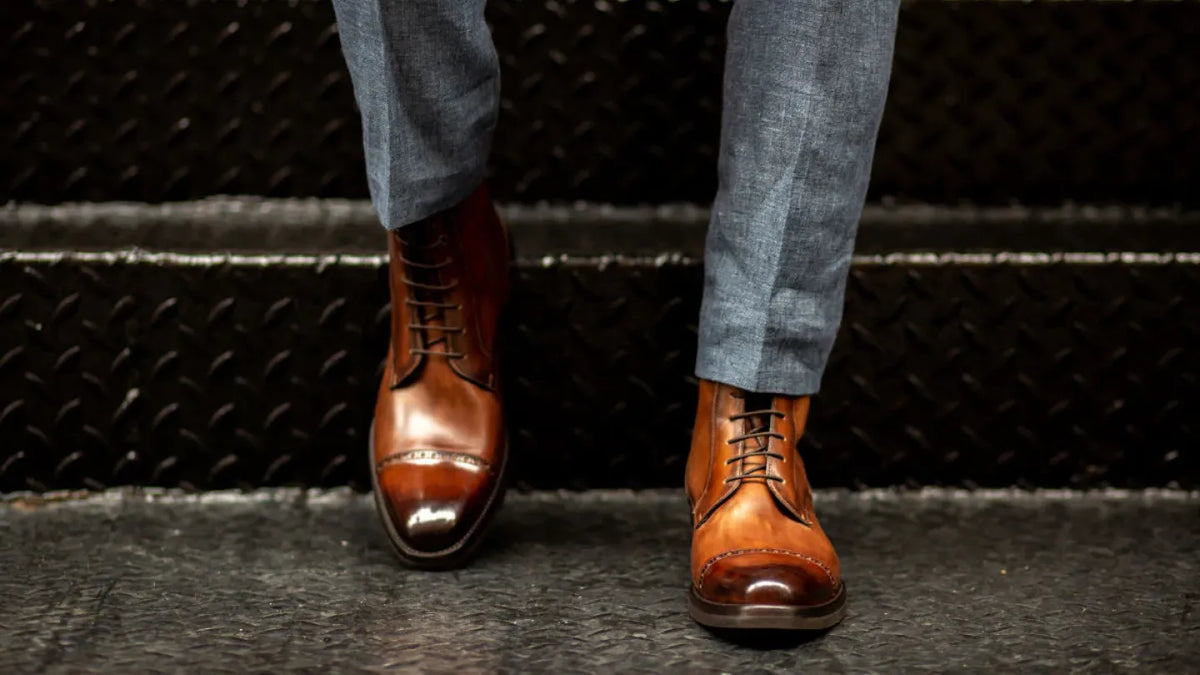 Man wearing polished brown dress shoes with gray trousers on industrial metal steps